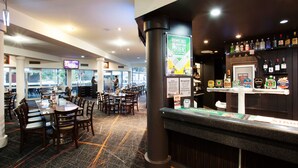 A restaurant with tables and chairs, a bar area with bottles, and a counter. - Vale Hotel (Aitkenvale)