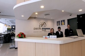 A reception desk at Pacific Express Hotel with a modern design, a logo, and a nameplate indicating room availability. - Pacific Express Hotel Central Market (Kuala Lumpur)