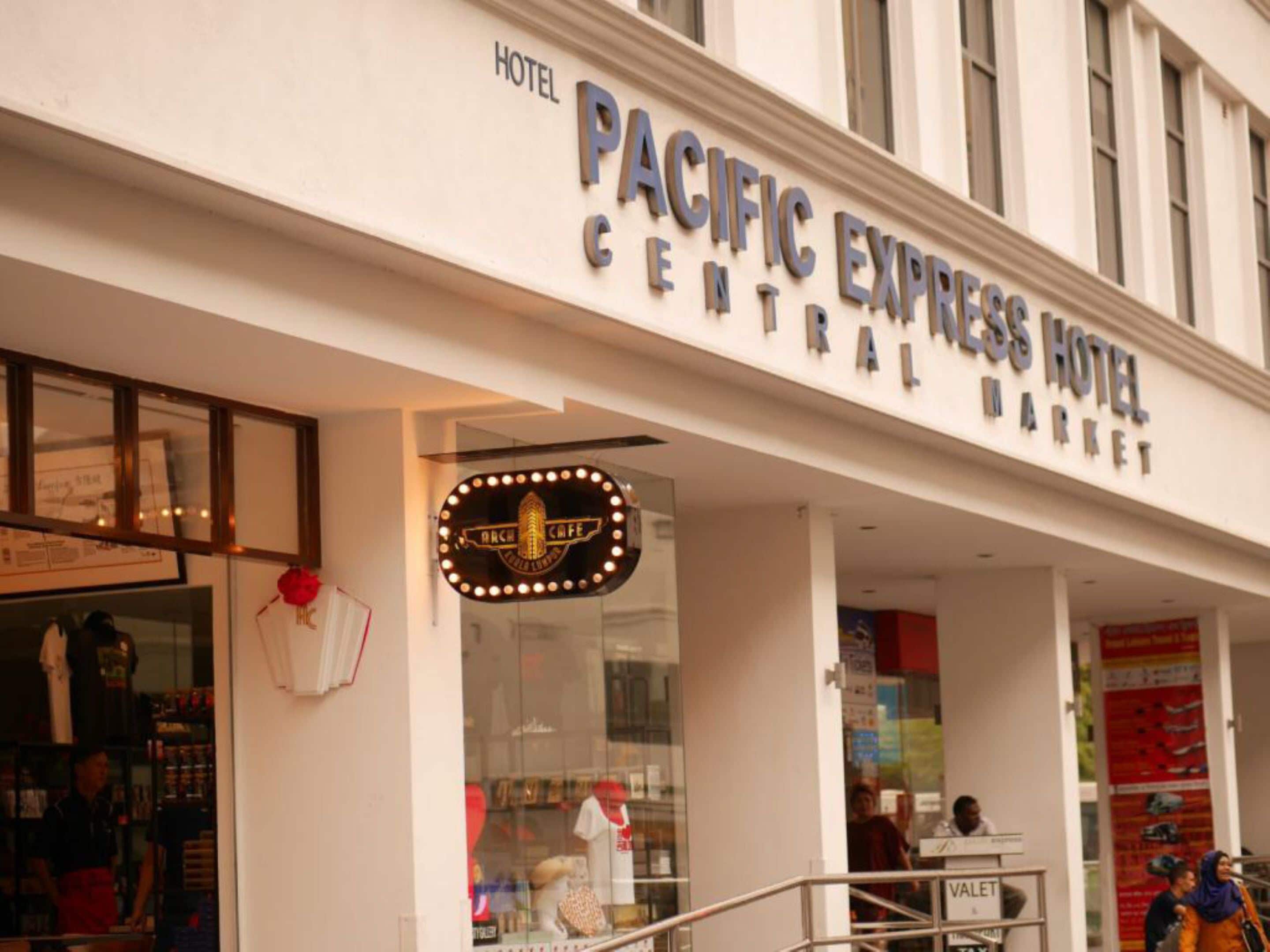 Exterior del Hotel Pacific Express Mercado Central, con un letrero llamativo y un escaparate donde se exhiben productos.