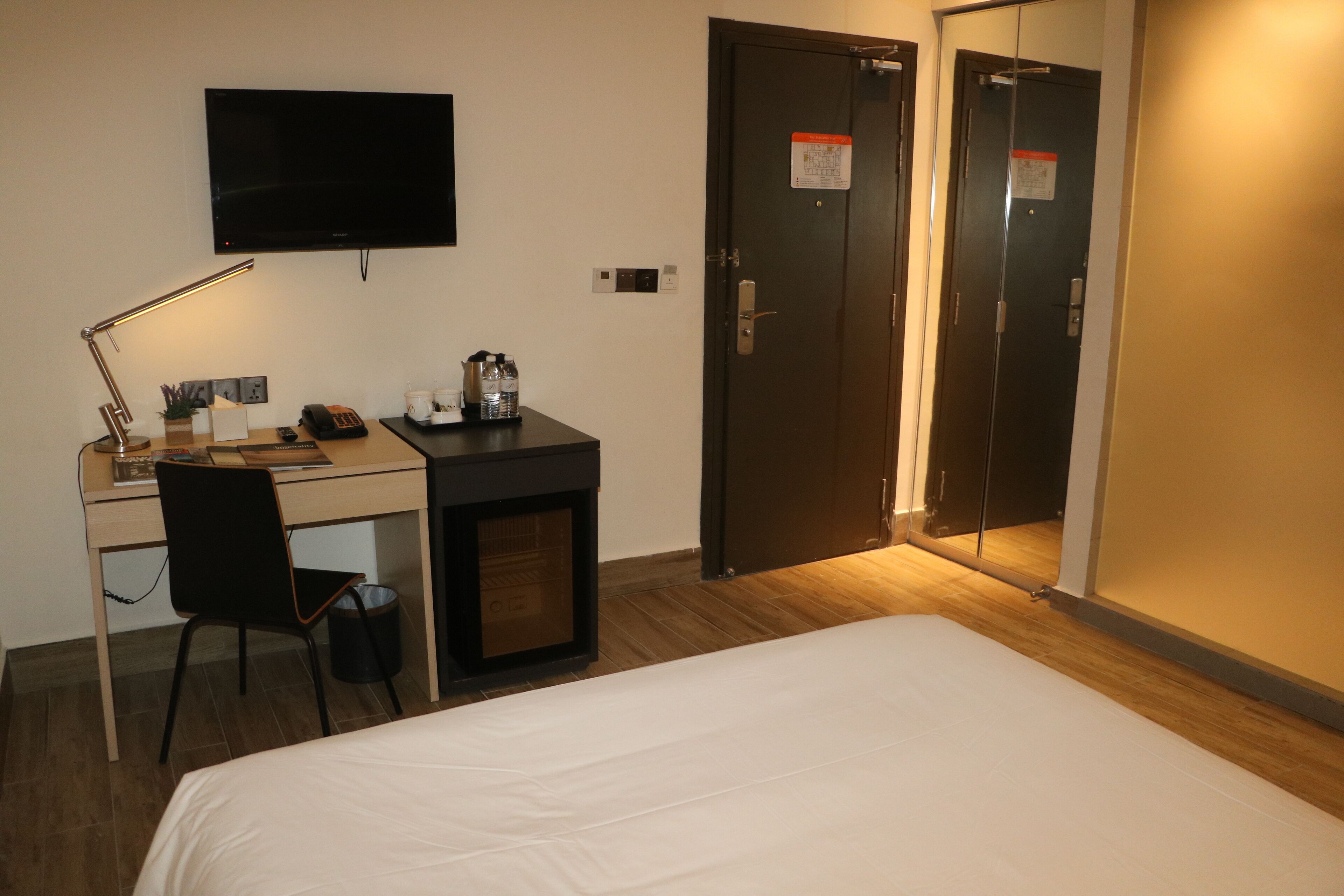 A hotel room with a bed, desk, chair, and a TV mounted on the wall.