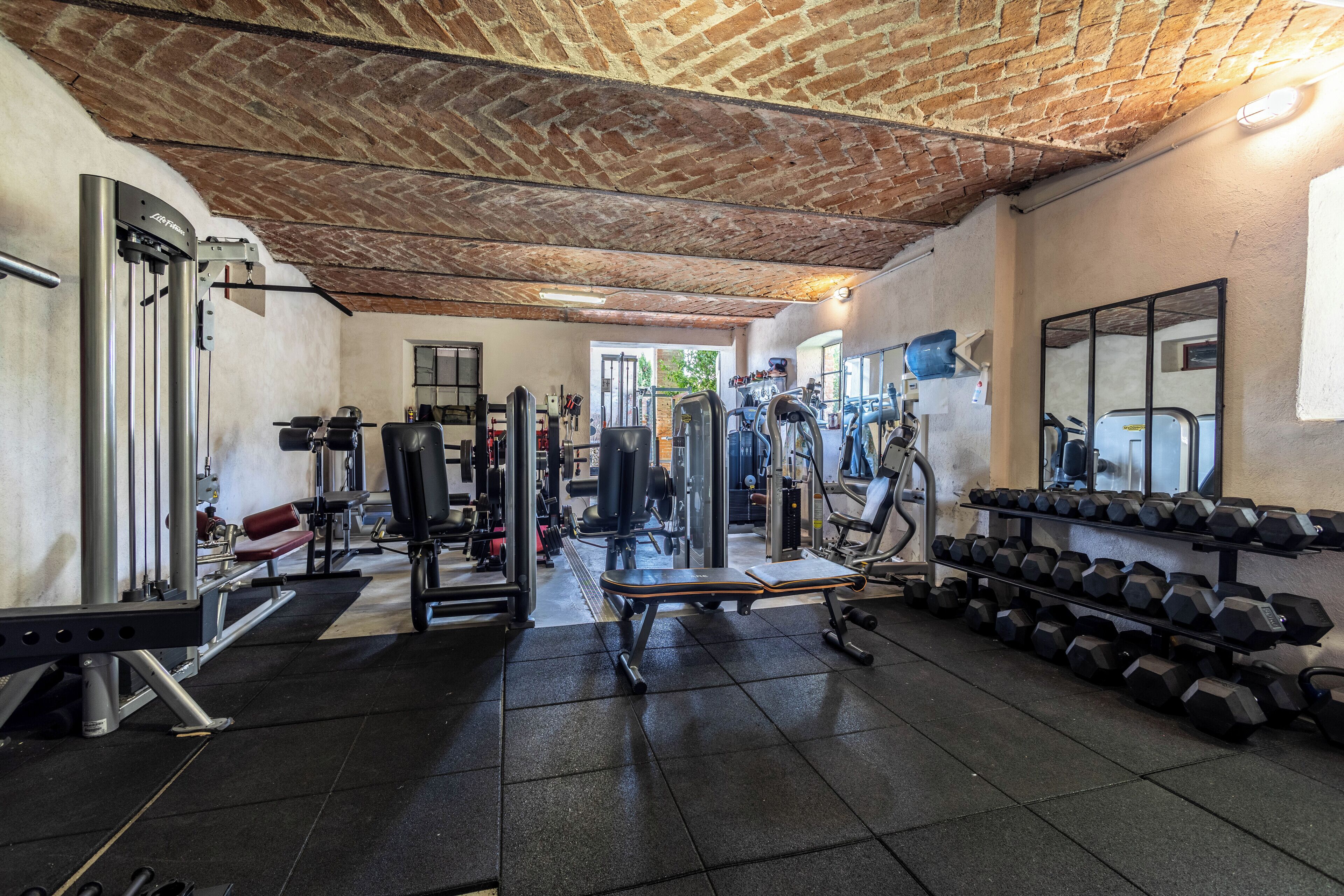 A gym with various exercise equipment, including dumbbells, benches, and weight machines.
