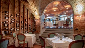 A restaurant with brick walls, wooden beams, and tables set for dining. - San martino langhe (Clavesana)