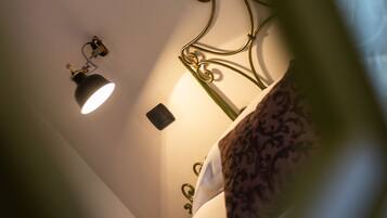 Un dormitorio con cama, una lámpara de pared y un cabecero metálico decorativo.