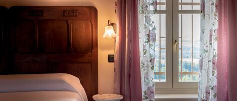 A bedroom with a wooden headboard, a bedside table, and a window with floral curtains.