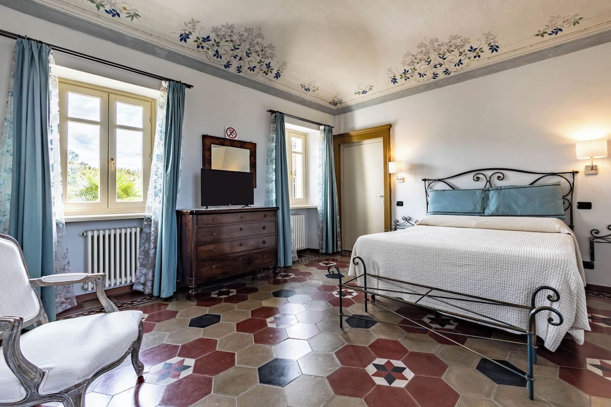 Un dormitorio con una cama, un aparador, una silla y un radiador.