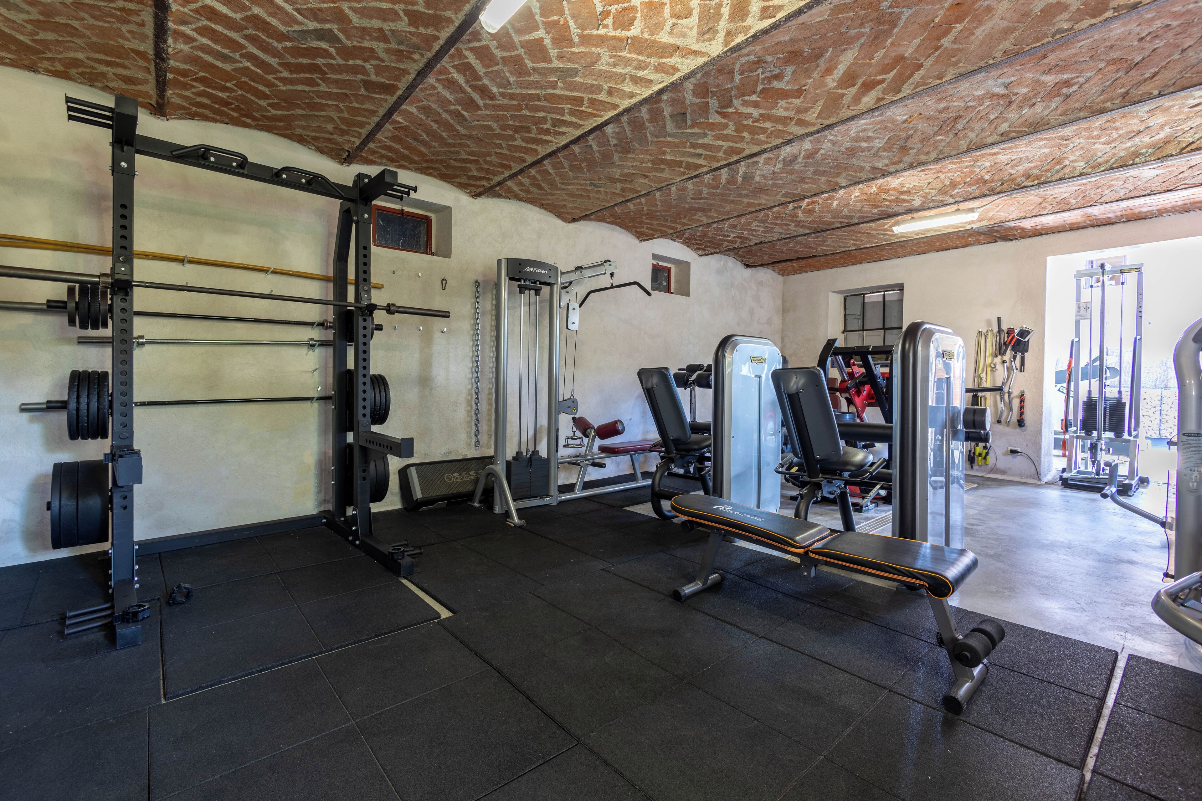Une salle de sport équipée de matériel de musculation, de bancs et d’un support pour les exercices de squat.