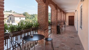 A covered outdoor area with a brick column, a round table, and two chairs. - San martino langhe (Clavesana)