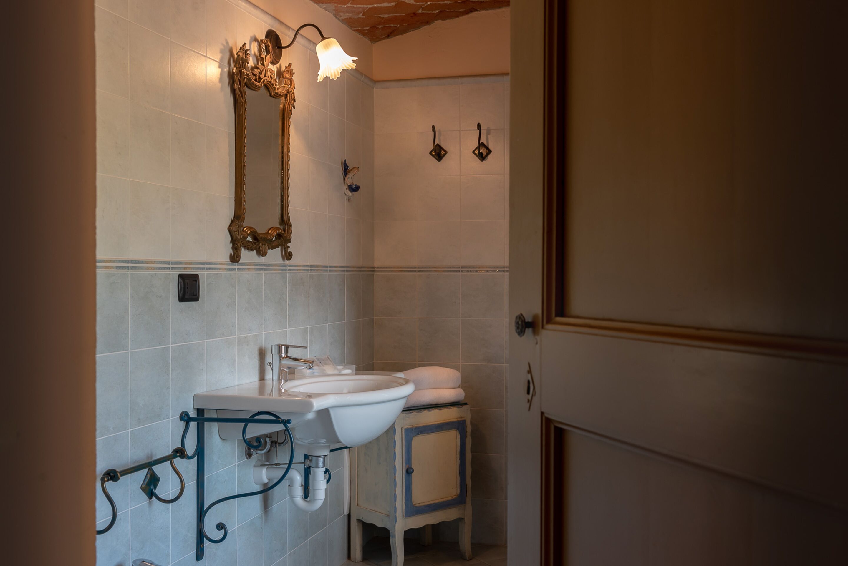 Casa de banho com uma pia branca, espelho e porta-toalhas.