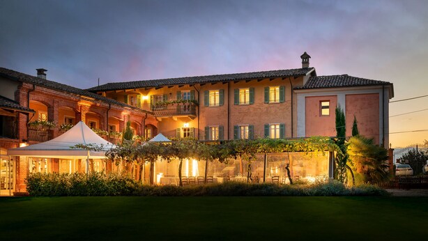 A large, multi-story building with a courtyard, featuring outdoor seating and a covered area. - San martino langhe (Clavesana)