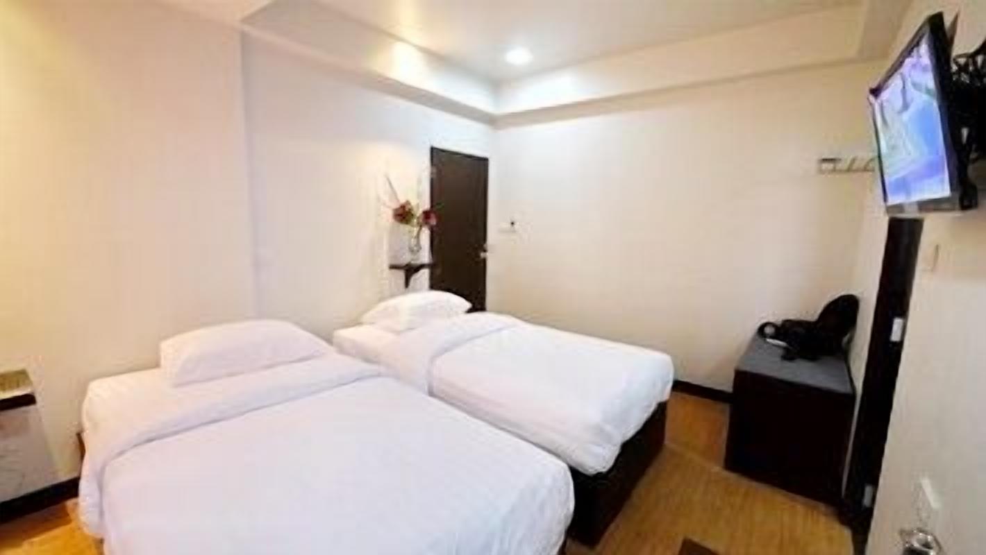 A hotel room with two single beds, a TV, and a small desk.