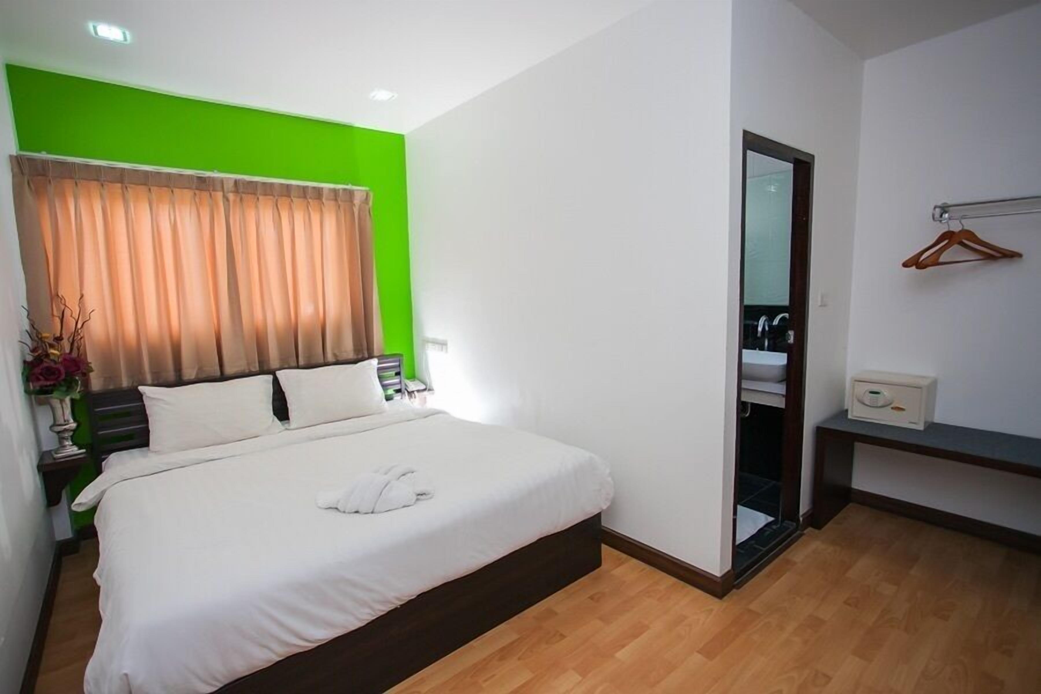 Ein Hotelzimmer mit einem Bett, einem Spiegel, einem Kleiderschrank und einem kleinen Nachttisch mit Lampe.