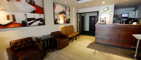 A hotel lobby with leather sofas, a reception desk, and artwork on the walls.