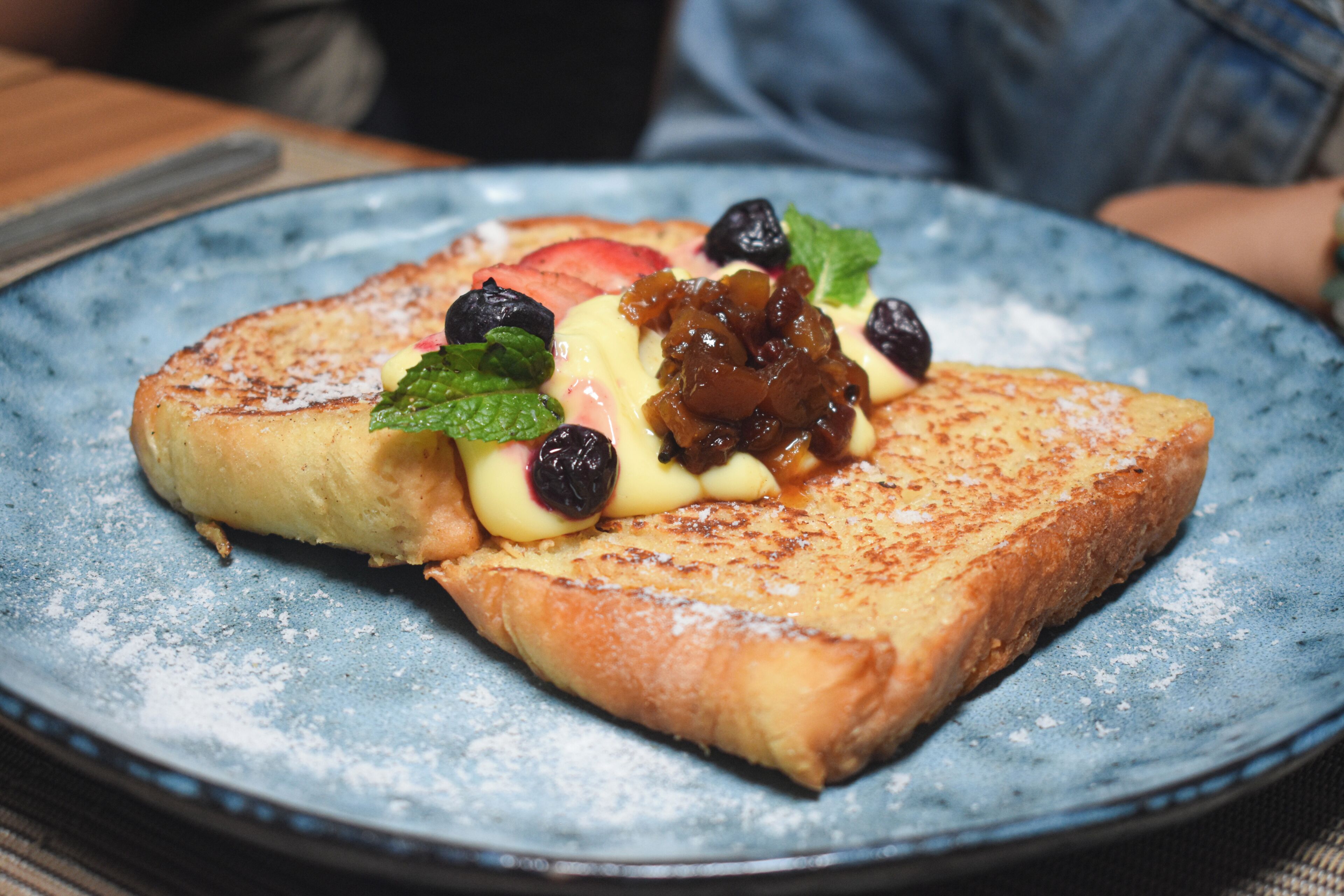 A plate with a slice of toast topped with fruit and a dollop of jam.