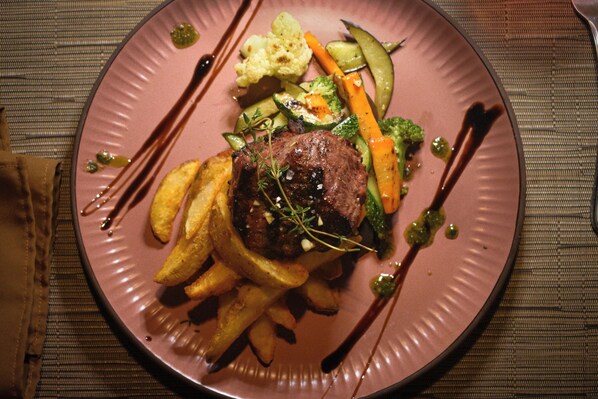 A plate with a steak, vegetables, and fries.