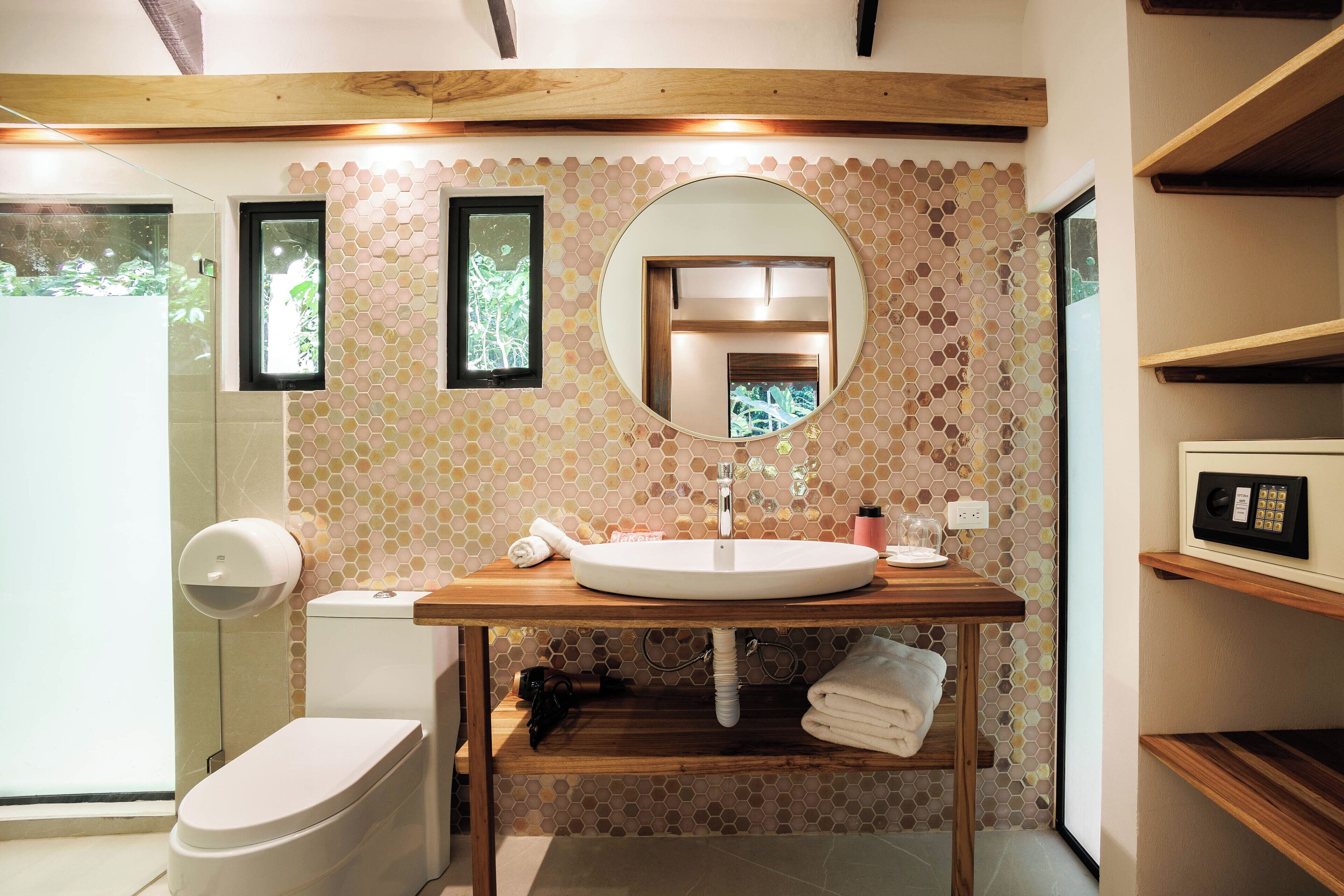 Ein modernes Badezimmer mit einem Holz-Waschtisch, einem runden Spiegel und einer Toilette.
