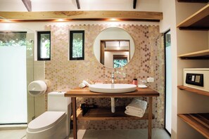 A modern bathroom with a wooden vanity, a round mirror, and a toilet.