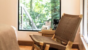 A wooden chair with a woven backrest and seat, positioned near a window with a view of greenery outside. - Almonds and Corals Boutique Hotel (Cahuita)