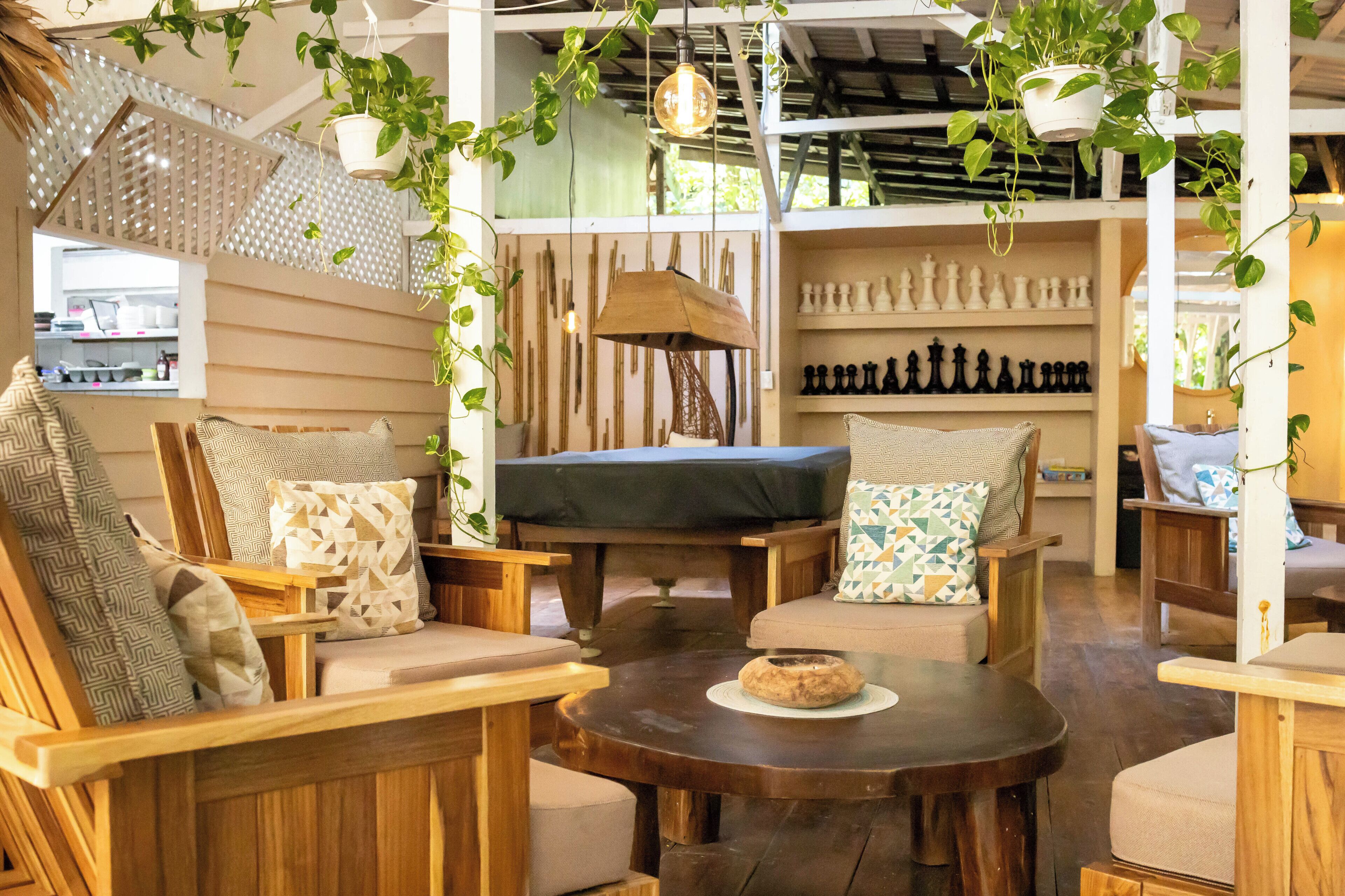 A cozy interior with wooden furniture, a chessboard, and hanging plants.