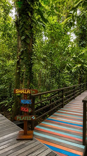 A wooden boardwalk with a sign indicating services like Shala, massages, yoga, and pilates. - Almonds and Corals Boutique Hotel (Cahuita)