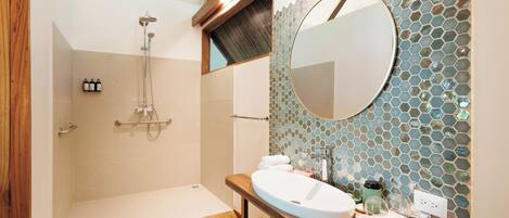 Un baño moderno con tocador de madera, un espejo grande y zona de ducha.