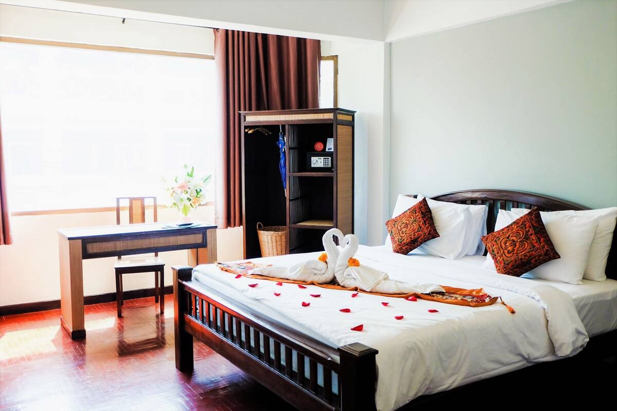 A hotel room with a wooden bed, a desk, and a wardrobe.