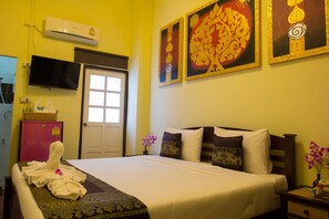A hotel room with a bed, a TV, a minibar, and artwork on the wall. - Sasima House (Chiang Mai)