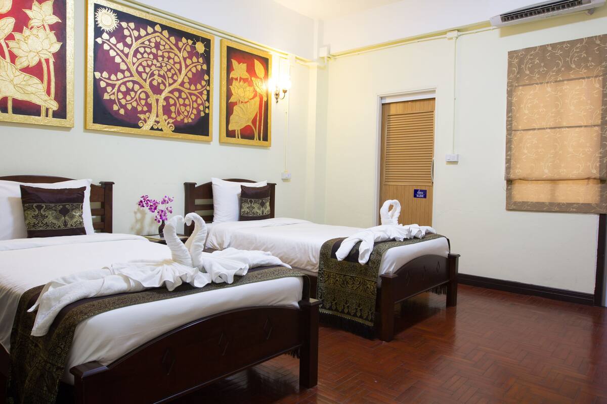 A hotel room with two beds, a wooden floor, and wall art.