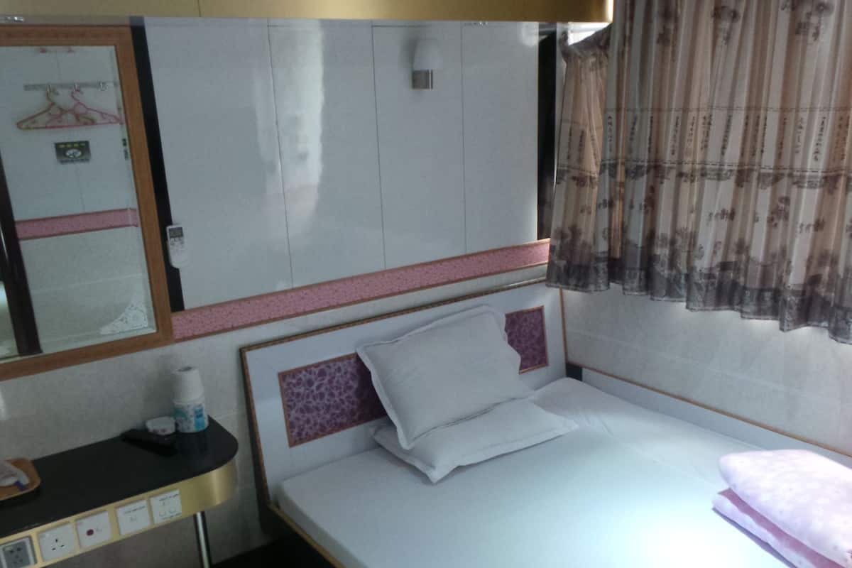 A hotel room with a bed, bedside table, and a mirror.