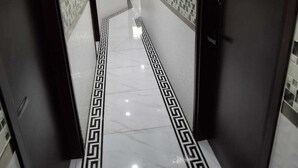 A hallway with a marble floor and a geometric pattern, leading to a door marked with the number 201. - Yue Ka Hotel (Kowloon)