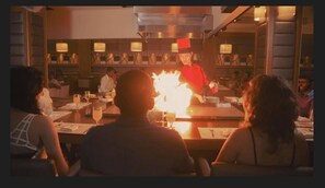 A restaurant interior with a chef performing a flambé.