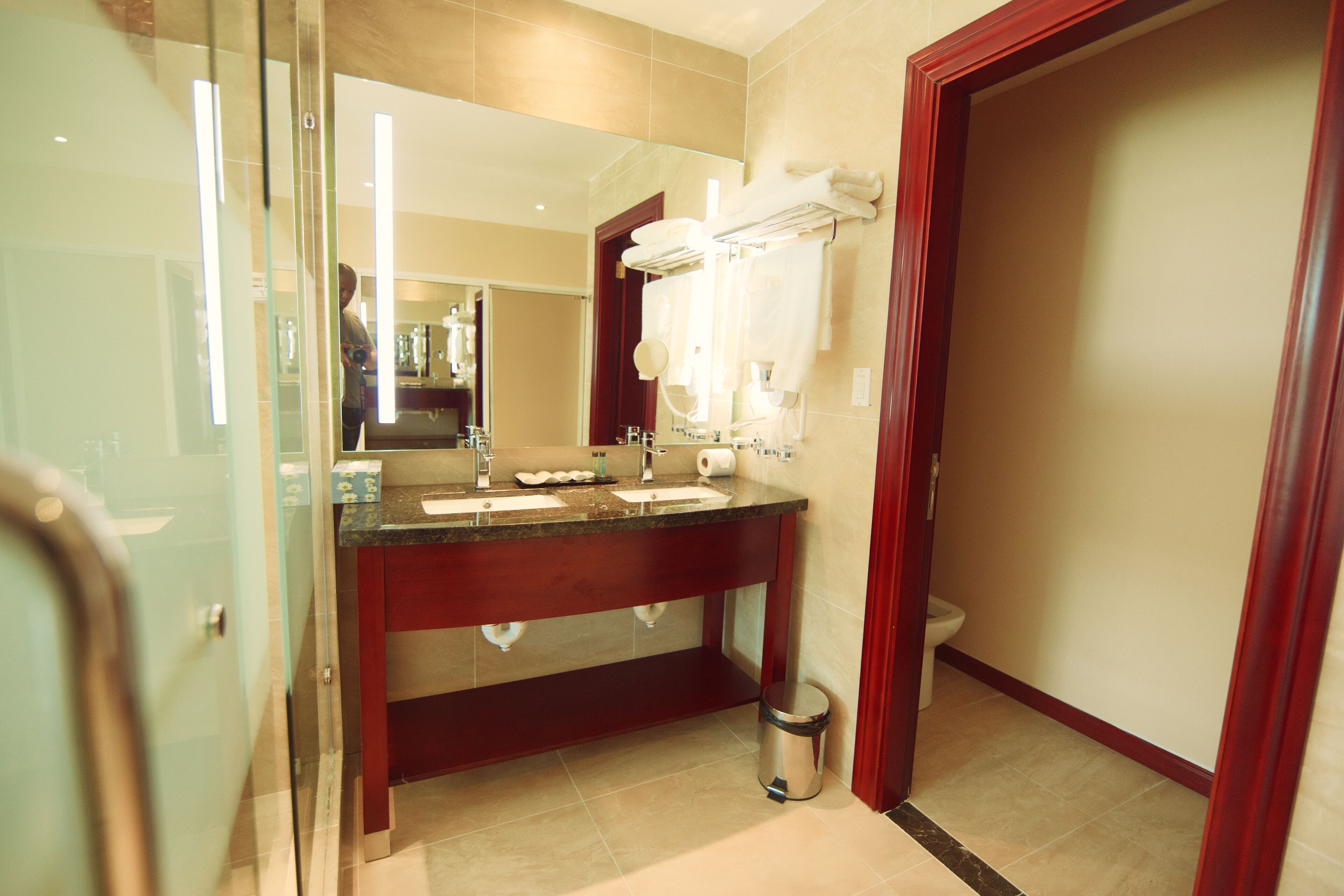 A modern bathroom with a glass shower enclosure, a double sink vanity, and a toilet.