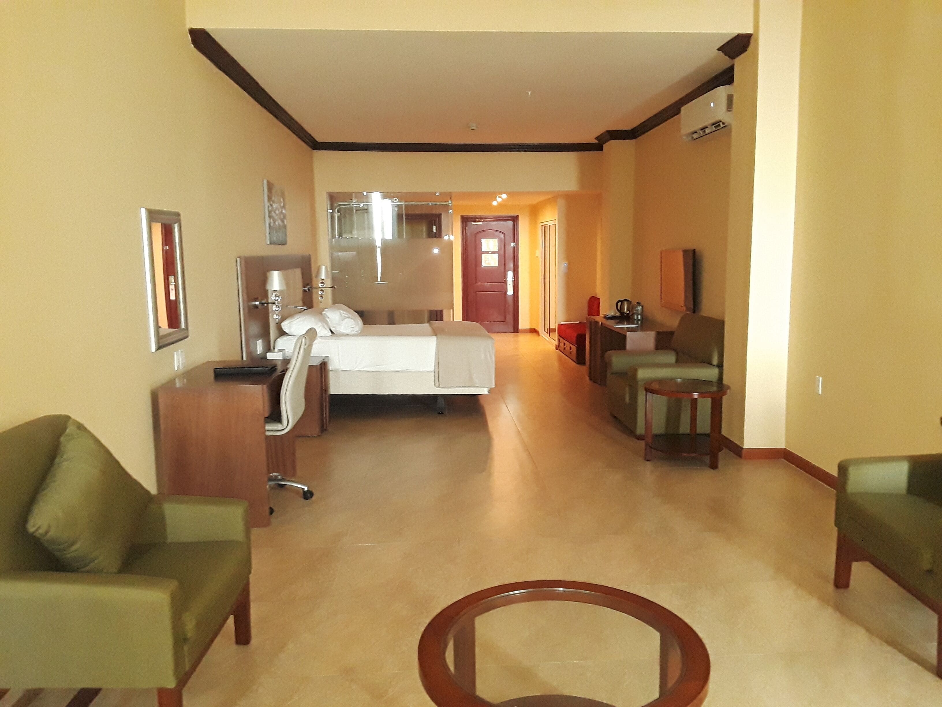 Ein Hotelzimmer mit Bett, Schreibtisch, Stuhl, Sofa und kleinem Tisch.