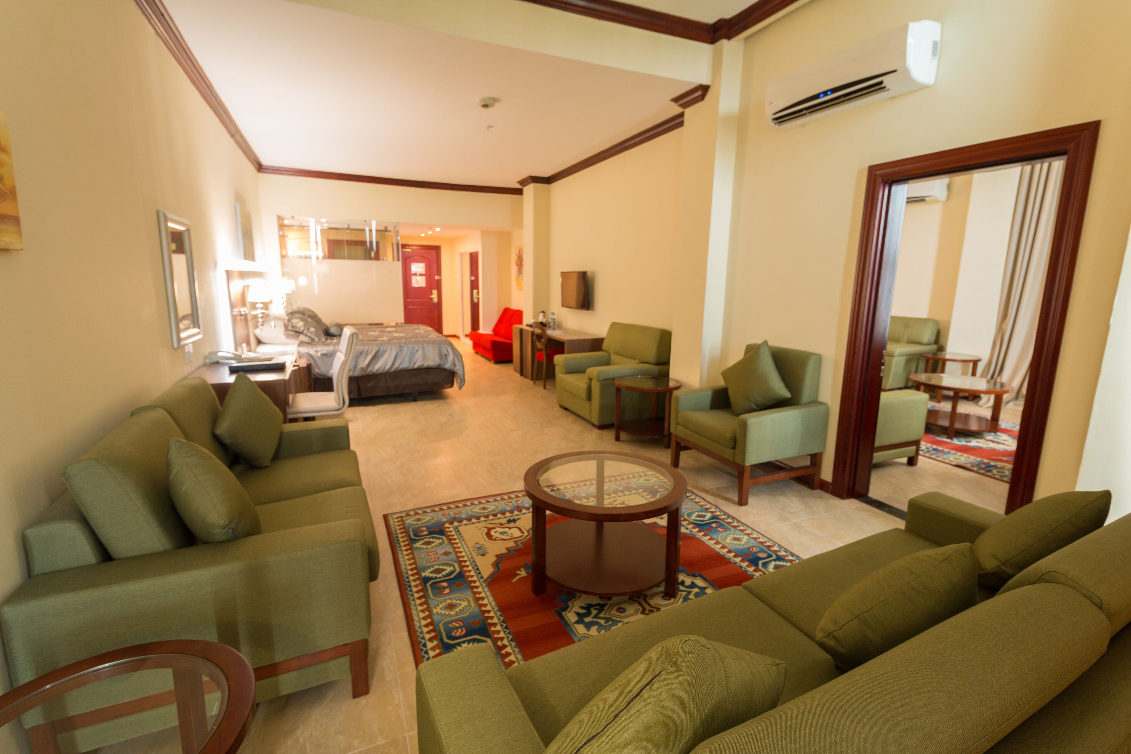 Una habitación de hotel con sala de estar, dormitorio, comedor y baño.