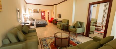 Una habitación de hotel con sala de estar, dormitorio, comedor y baño.