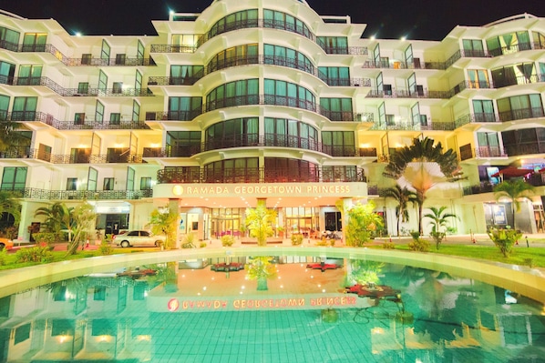 A multi-story hotel with a pool in the foreground.
