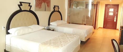 Een hotelkamer met twee bedden, een grote spiegel en een deur naar een gang.