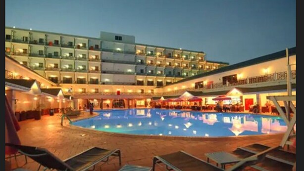 A hotel with a swimming pool, outdoor seating, and a multi-story building with balconies. - Ramada Georgetown Princess Hotel (Georgetown)