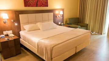 A hotel room with a large bed, a bedside table with a phone, a lamp, and a chair.