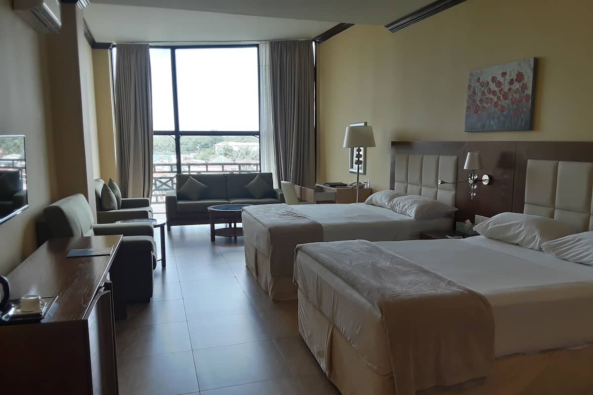 A hotel room with two beds, a sofa, a small table, and a TV.