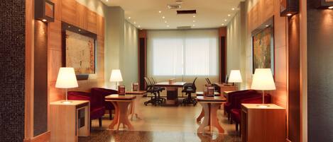 Een moderne hotellobby met een vergadertafel, comfortabele zithoek en een groot raam.