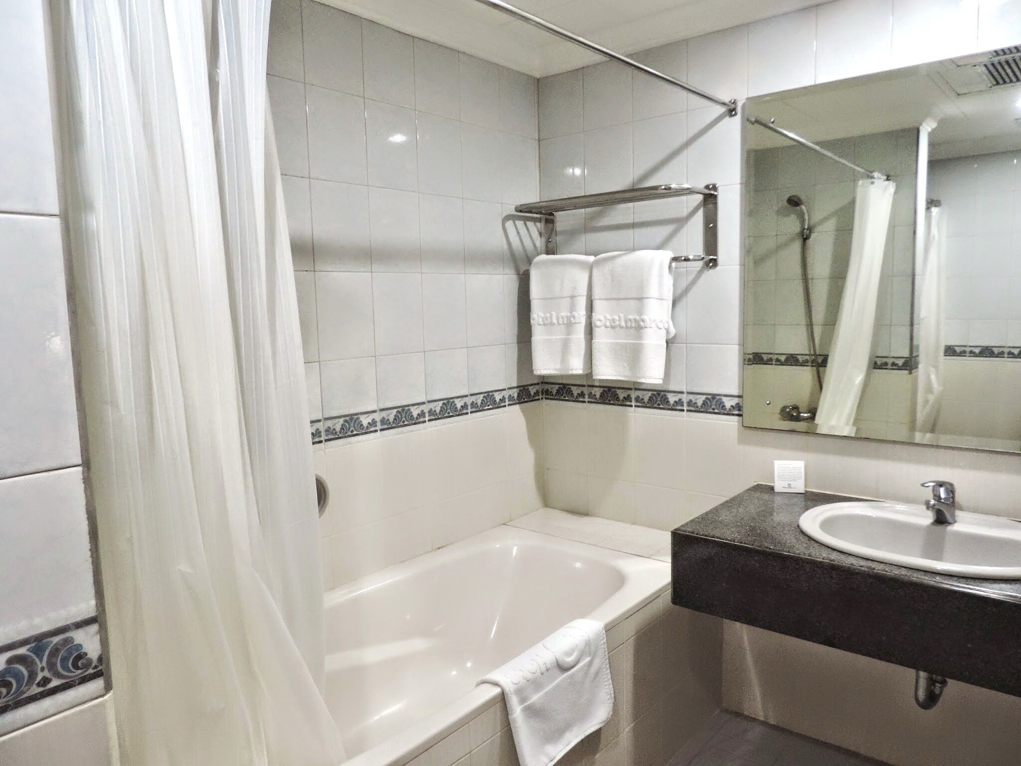 Un baño con una bañera, un lavamanos y un espejo.