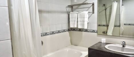Un baño con una bañera, un lavamanos y un espejo.