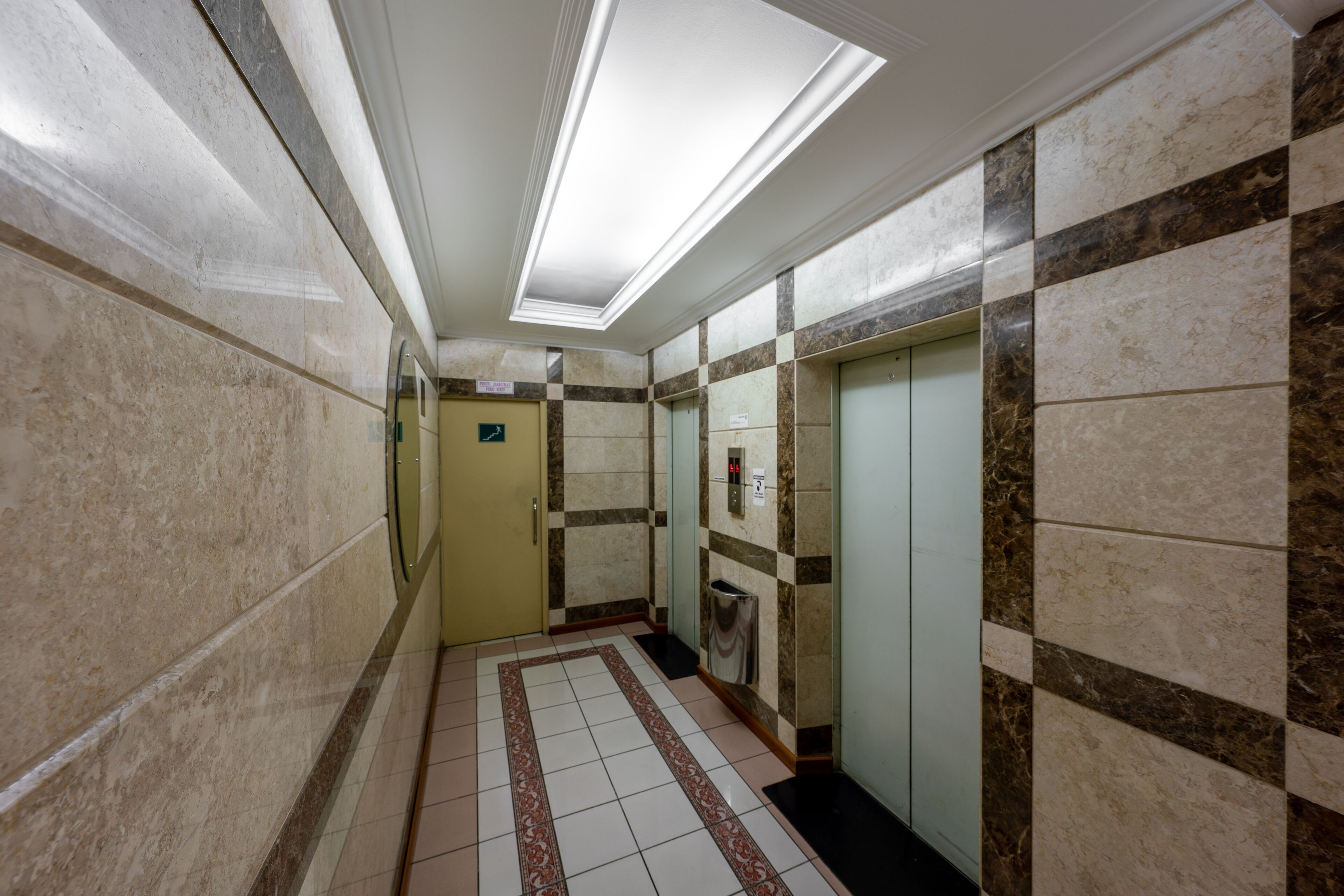 Un corridoio con pareti in marmo, pavimento piastrellato e una luce a soffitto.