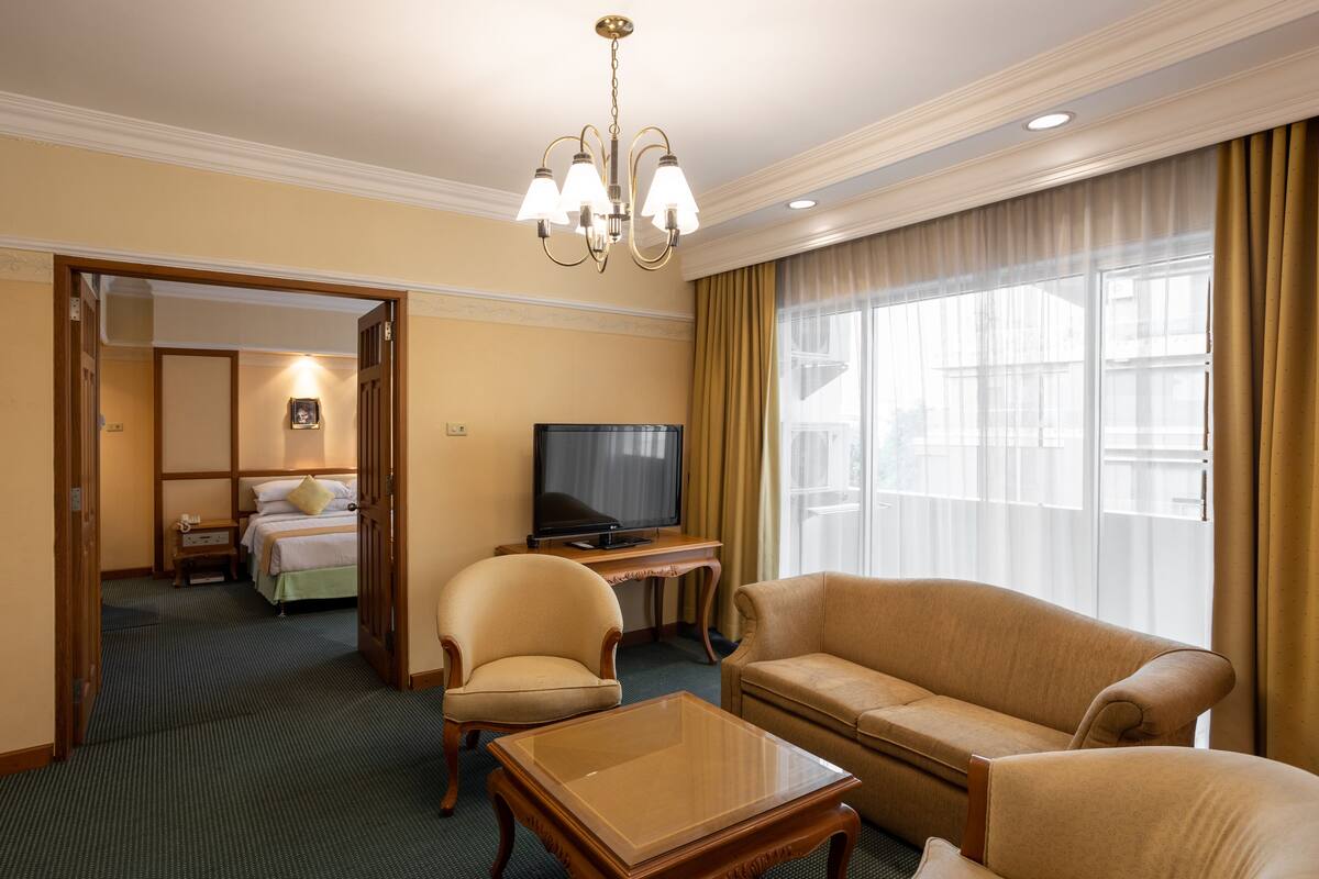 Una habitación de hotel con cama, televisor, sofá, sillón y escritorio.