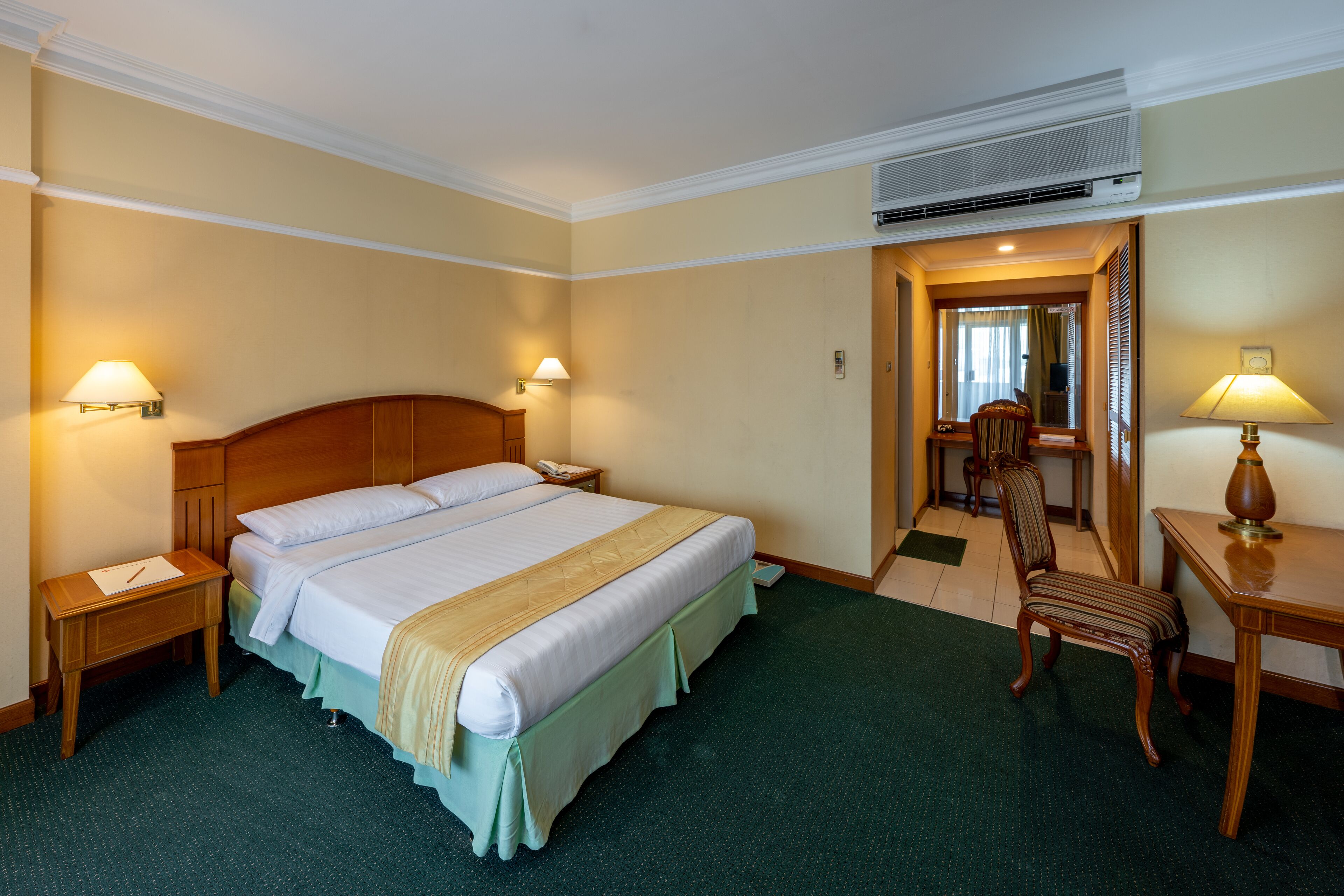 Une chambre d’hôtel avec un grand lit, deux tables de chevet, un bureau avec une chaise et un miroir.