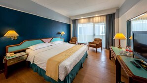 A hotel room with a large bed, two armchairs, a desk with a TV, and a window with curtains. - Hotel Marcopolo Jakarta (Jakarta)