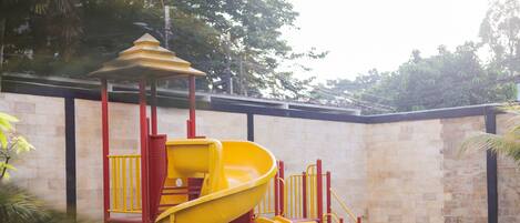 A playground with a yellow slide and climbing structures.