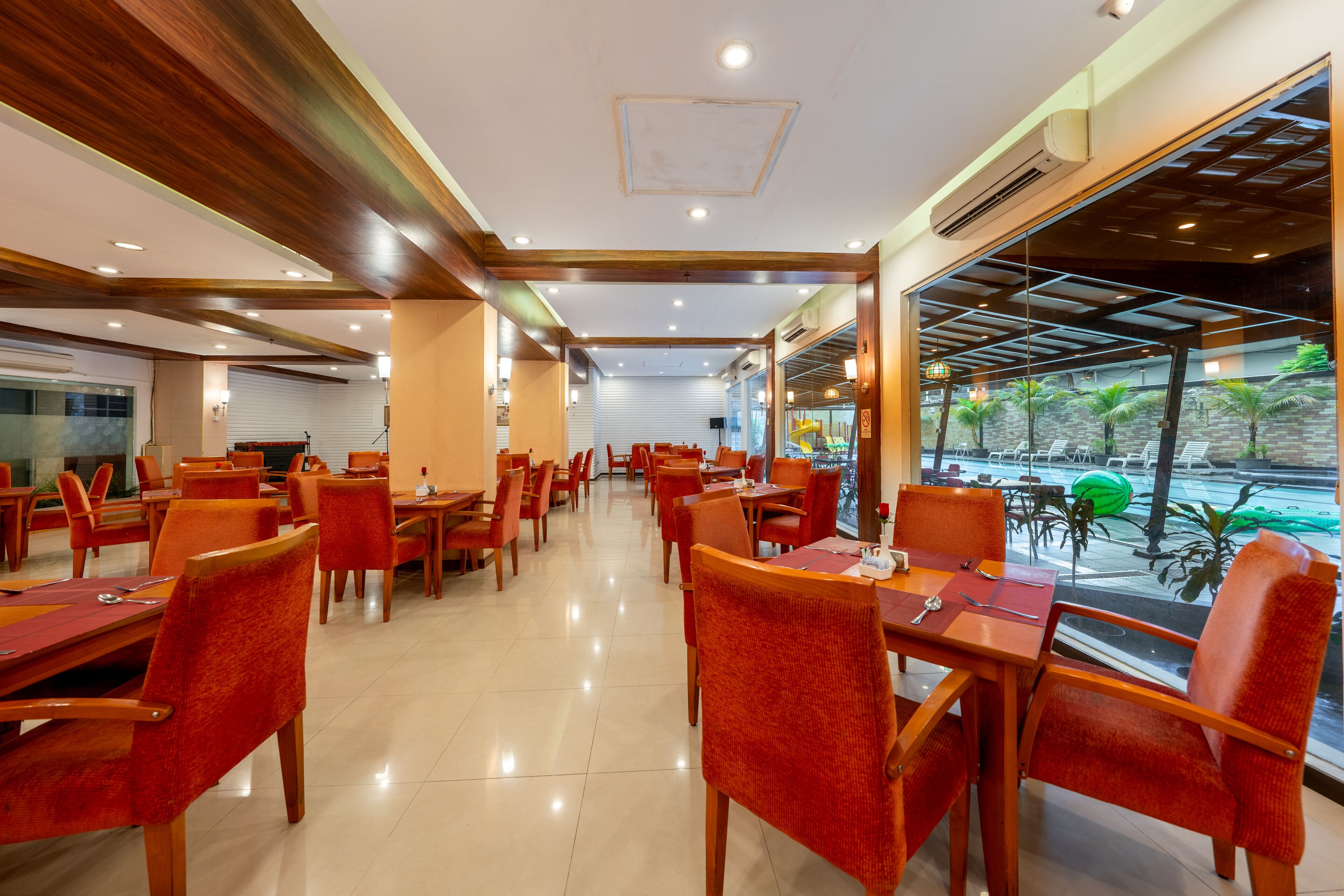 Un restaurant avec des poutres en bois au plafond, des chaises rouges et des tables.