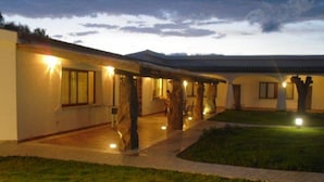 A building with multiple rooms, a covered outdoor area, and a grassy lawn.