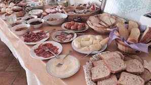 A buffet table with various food items including meats, cheeses, and bread.